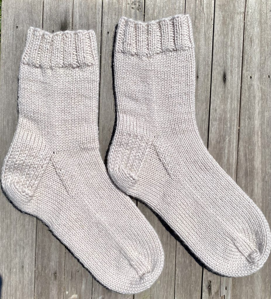 pair of color 2 drops fiesta knit dk socks on wood background