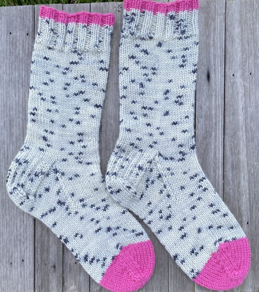 pair of dk knit socks in drops fiesta ink spots and cerise on wood background