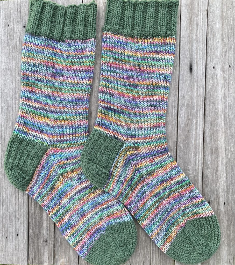 pair of dk knit socks drops fiesta yarn garden party and dark ivy on wood background