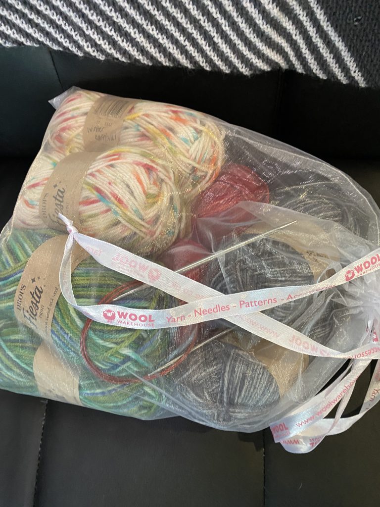 sheer organza bag from wool warehouse with balls of drops fiesta sock yarn inside on black background