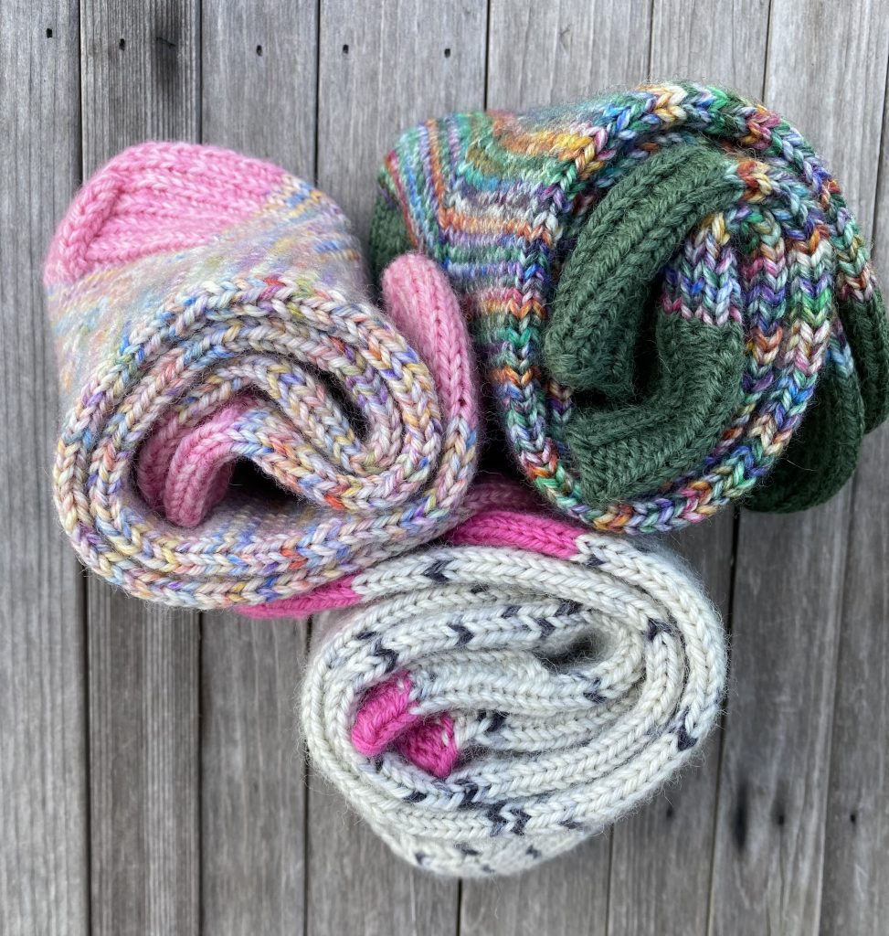 3 pairs of patterned wool socks rolled up and positioned together on a wood slat background